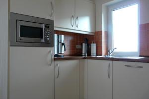a kitchen with a microwave on top of a refrigerator at Ferienhaus direkt an See & Strand in Göhren-Lebbin