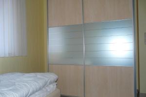 a bedroom with a large glass closet with a bed at Ferienhaus direkt an See & Strand in Göhren-Lebbin