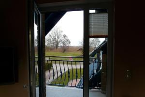 an open door to a balcony with a view of a park at Ferienhaus direkt an See & Strand in Göhren-Lebbin +1 photo