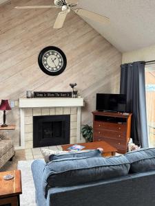 a living room with a clock above a fireplace at Condo,Full Kitchen, ShantyCreek, Beach Club, Private Pool in Bellaire +24 photos
