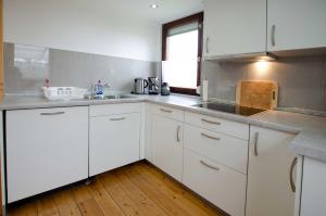 una cucina con mobili bianchi e pavimento in legno di Bungalow Merla - Kemnitz a Dahme