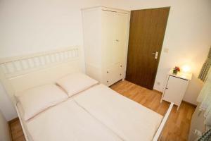 Schlafzimmer mit einem weißen Bett und Holzboden in der Unterkunft Appartment 1614, Ferienpark Oberallgäu, Schwimmbad, Sauna, Spielplatz in Missen-Wilhams + 14 Fotos