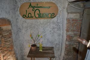 a sign on a wall with a table with a plant at Agriturismo La Querce in Rignano sullʼArno