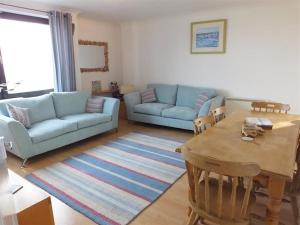 a living room with a table and a blue couch at Harbour View Saundersfoot in Saundersfoot