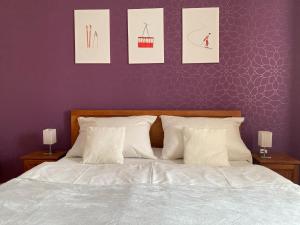 a bedroom with a white bed with three pictures on the wall at Penzion Plesnivec in Poprad