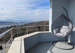 a hanging chair on a balcony with a view of the water at Anai Jadranovo in Jadranovo