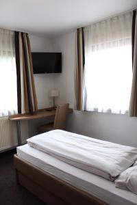 a bedroom with a bed and a desk and a television at Pension Mavi in Steinmauern