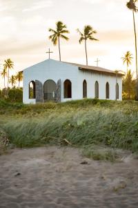 an old church on a beach with palm trees at Casa de Condomínio ao lado da Capela de Milagres in São Miguel dos Milagres +29 photos