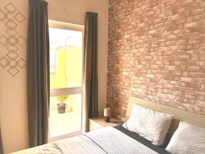 a bedroom with a brick wall and a bed and a window at Arzella Apartments Xlendi Stylish Stay Near Beach Local Eats in Xlendi