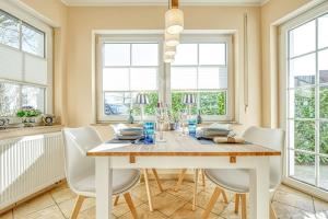 ein Esszimmer mit Tisch und Stühlen und Fenstern in der Unterkunft An der alten Rotbuche 02 in Zingst