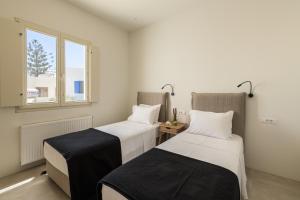 two beds in a room with a window at Azimuth Houses in Pollonia
