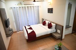 a bedroom with a bed with red pillows at Hotel Sun Bright Residency Manipal in Manipala +20 photos