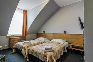 a bedroom with two beds and a tv and a window at Hotel Galion in Gdańsk