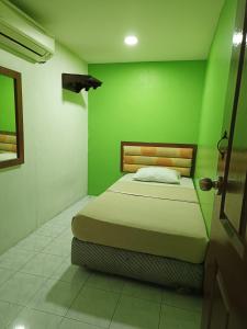 una camera verde con un letto in una stanza di HOTEL MEDAN KiDD a Ipoh