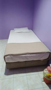 un letto in una camera da letto con parete viola di HOTEL MEDAN KiDD a Ipoh