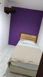 Posto letto in camera con parete viola di HOTEL MEDAN KiDD a Ipoh