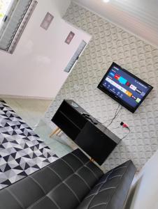 a living room with a couch and a television on a counter at Casinha no Centro in Santo Antônio do Pinhal