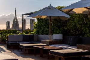 a patio with couches and tables and an umbrella at Hotel 1898 in Barcelona
