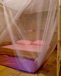 a bed covered in mosquito nets on a wooden floor at Bamboo Village in Ban Tai
