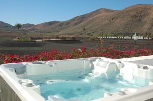 a jacuzzi tub in a garden with pink flowers at La Casona de Yaiza I Hotel Emblematico in Yaiza