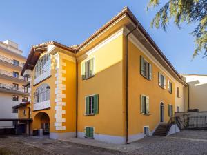 a yellow building with green windows and stairs at Appartamento Jazz 1 in Muralto