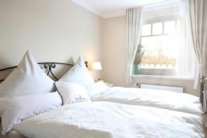 a white bed with white pillows and a window at Haus am Park Whg13 in Spiekeroog