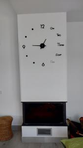 eine Uhr an einer weißen Wand neben einem Fernseher in der Unterkunft La Casita de la Piscina in Burguillos de Toledo