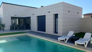 ein Haus mit einem Pool und zwei Stühlen in der Unterkunft La Casita de la Piscina in Burguillos de Toledo