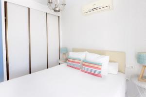 biała sypialnia z białym łóżkiem z 2 poduszkami w obiekcie La Marina Suite Málaga w Maladze
