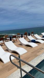 a row of white lounge chairs and tables on a deck at 805 Vista Mar Aconchegante in Salvador