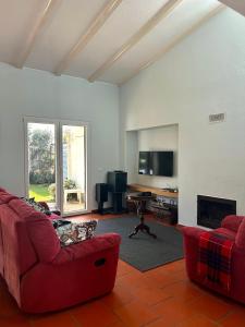 a living room with a red couch and a tv at Vila Mar in Porto Covo