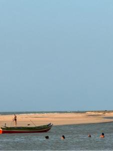 a group of people in the water next to a boat at Casa de Praia em Maceió - Camocim - CE in Camocim