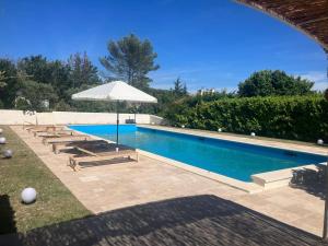 a swimming pool with an umbrella and lounge chairs and sidx sidx sidx at Villa Paradis des Oréades in Lauris
