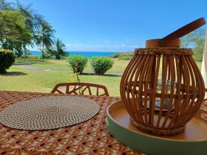 une table avec un vase assis au-dessus dans l'établissement Studio Ti Karanbol RDC vue mer dans Résidence de Tourisme, à Sainte-Anne