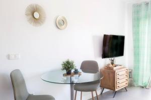 Biały salon ze szklanym stołem i krzesłami w obiekcie La Marina Suite Málaga w Maladze