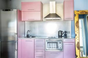 kuchnia z różowymi szafkami i lodówką ze stali nierdzewnej w obiekcie La Marina Suite Málaga w Maladze