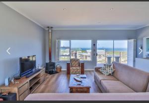 a living room with a couch and a tv at OceansCrest Seaview Apartment in Bettyʼs Bay