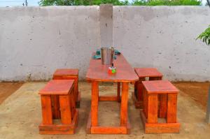 a wooden picnic table with four stools around it at Lux-sit Guesthouse in Kasane
