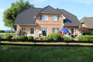 a brick house with people sitting under a blue umbrella at Bauernhof Höper-Rauert - Nr 10 Wellnesshaushälfte in Neujellingsdorf