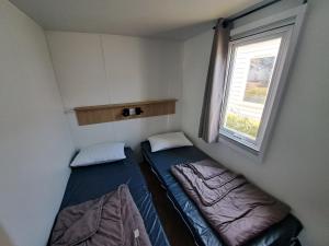 ein kleines Zimmer mit zwei Betten und einem Fenster in der Unterkunft Houlgate Mobilhome,3ch, 6pl, camp 5 étoiles, piscines, club enfants in Houlgate + 20 Fotos