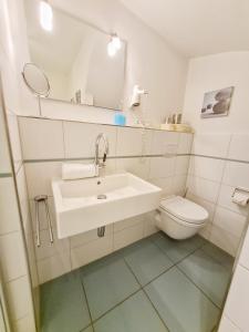 a white bathroom with a sink and a toilet at Schwalbennest in Wyk auf Föhr