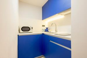 eine Küche mit blauen Schränken und einer Mikrowelle in der Unterkunft Iconic Suites in Madrid