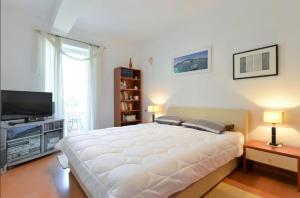 a bedroom with a large white bed and a flat screen tv at Apartments Doda in Zadar