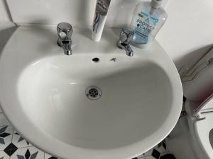 a white bathroom sink with two bottles of toothpaste at A Place to stay in Kettering in Kettering