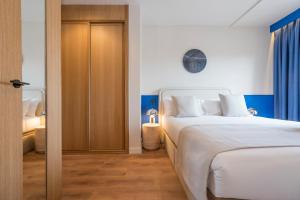 ein Schlafzimmer mit einem weißen Bett und einer Holztür in der Unterkunft Iconic Suites in Madrid