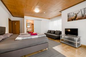 a bedroom with a bed and a tv and a couch at Gästehaus Friedlich in Schönau am Königssee