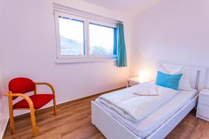 a bedroom with a bed and a red chair at City Dream 1 by Alpenidyll Apartments in Schladming +7 photos