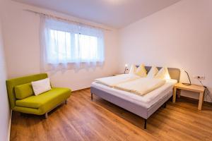 a bedroom with a bed and a green chair at City Dream 1 by Alpenidyll Apartments in Schladming