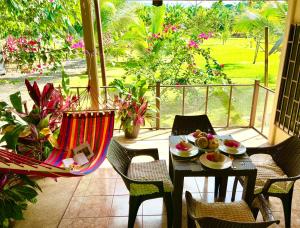 a table and chairs on a porch with a table and chairs at Casa Tropical Ceiba in Puerto Jiménez