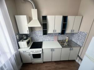a small kitchen with white cabinets and a sink at LUX HOME на Дворце Металлургов in Ustʼ-Kamenogorsk